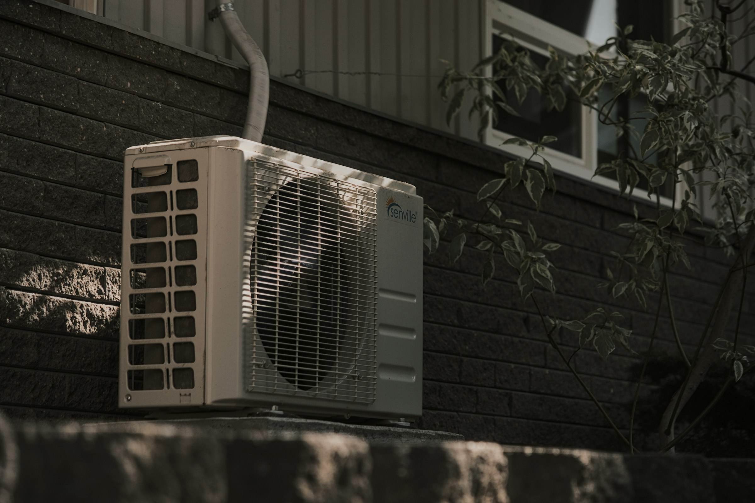 An air conditioner condenser on the side of a house