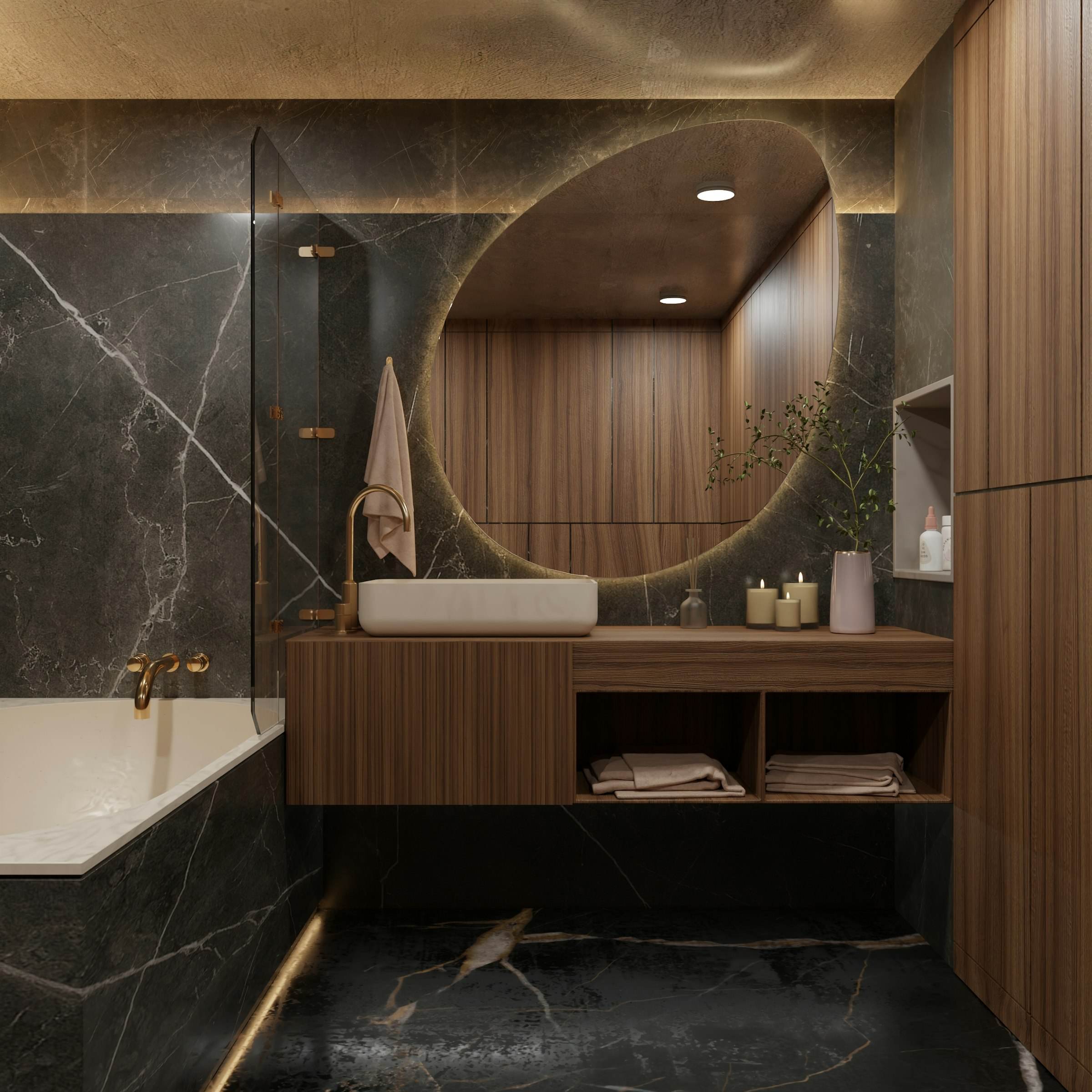 A bathroom with dark stone walls, a walnut vanity and a round lit mirror