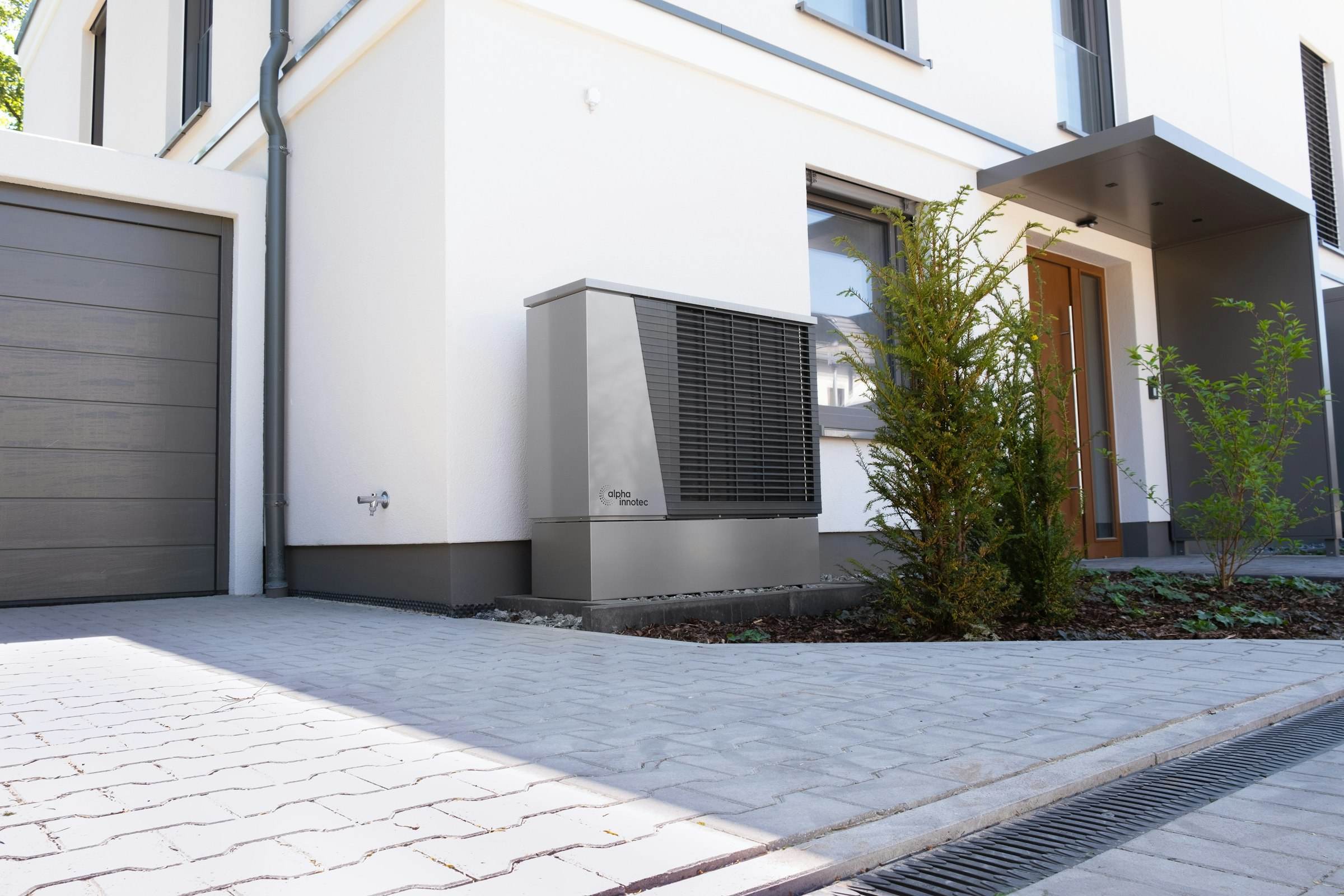 A heat pump unit beside the driveway of a modern house