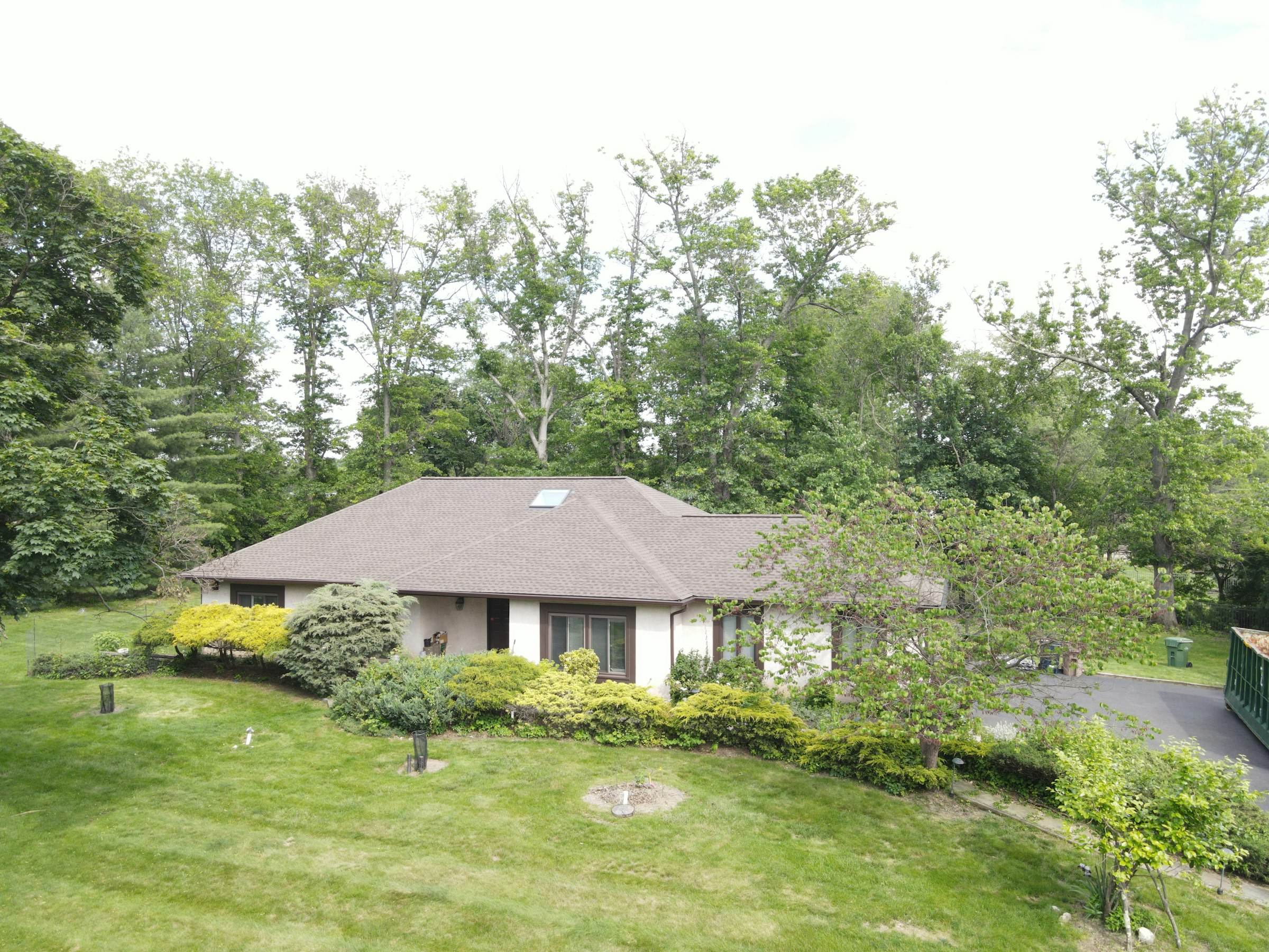 A single-story home with a low-pitch roof among trees on a hillside