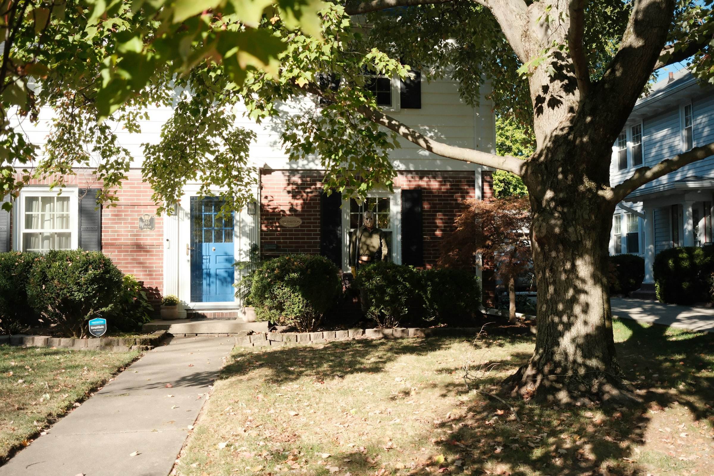 A suburban house with a blue front door shaded by trees