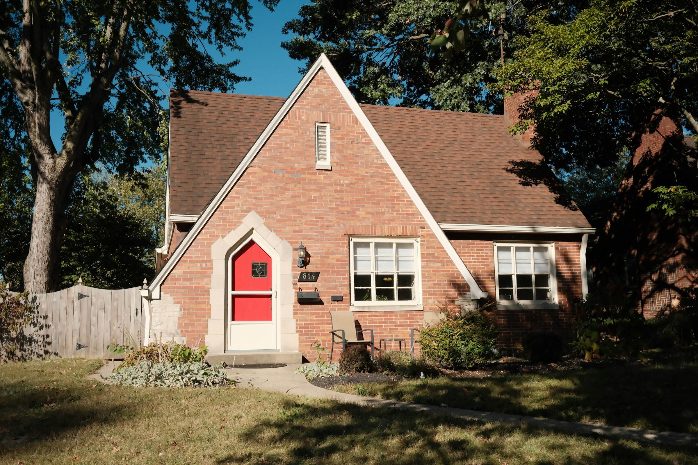 A brick house with a red front door and a lawn