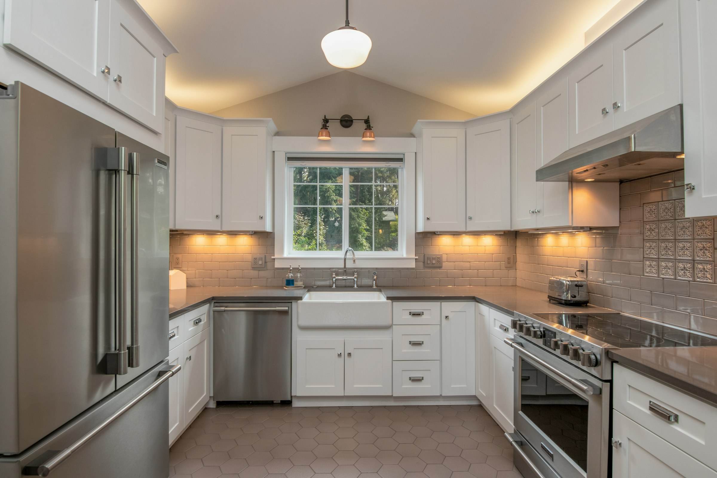 A white kitchen with copper pendant lights and a long counter