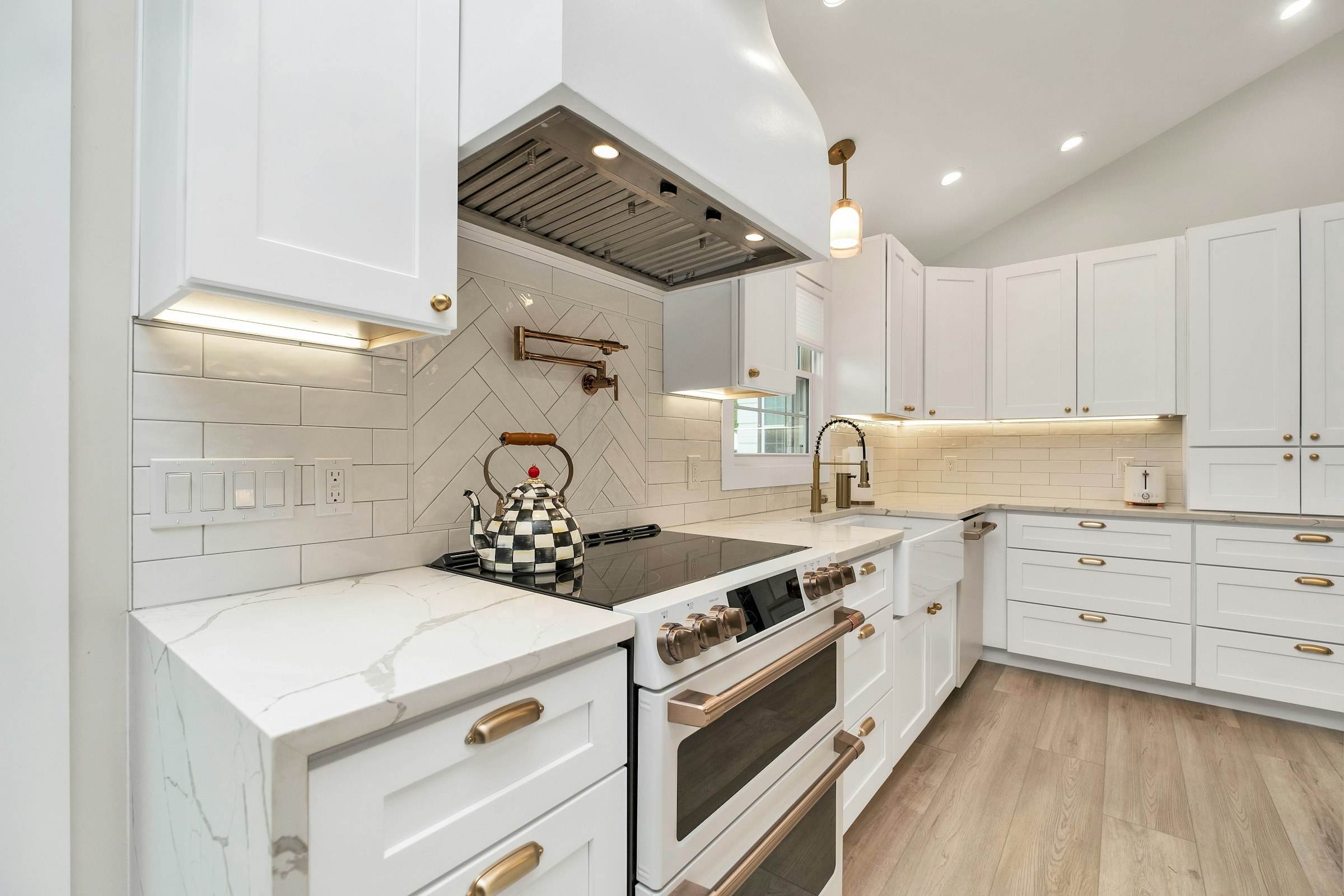 White cabinetry, a range wall and brass fixtures in a renovated kitchen