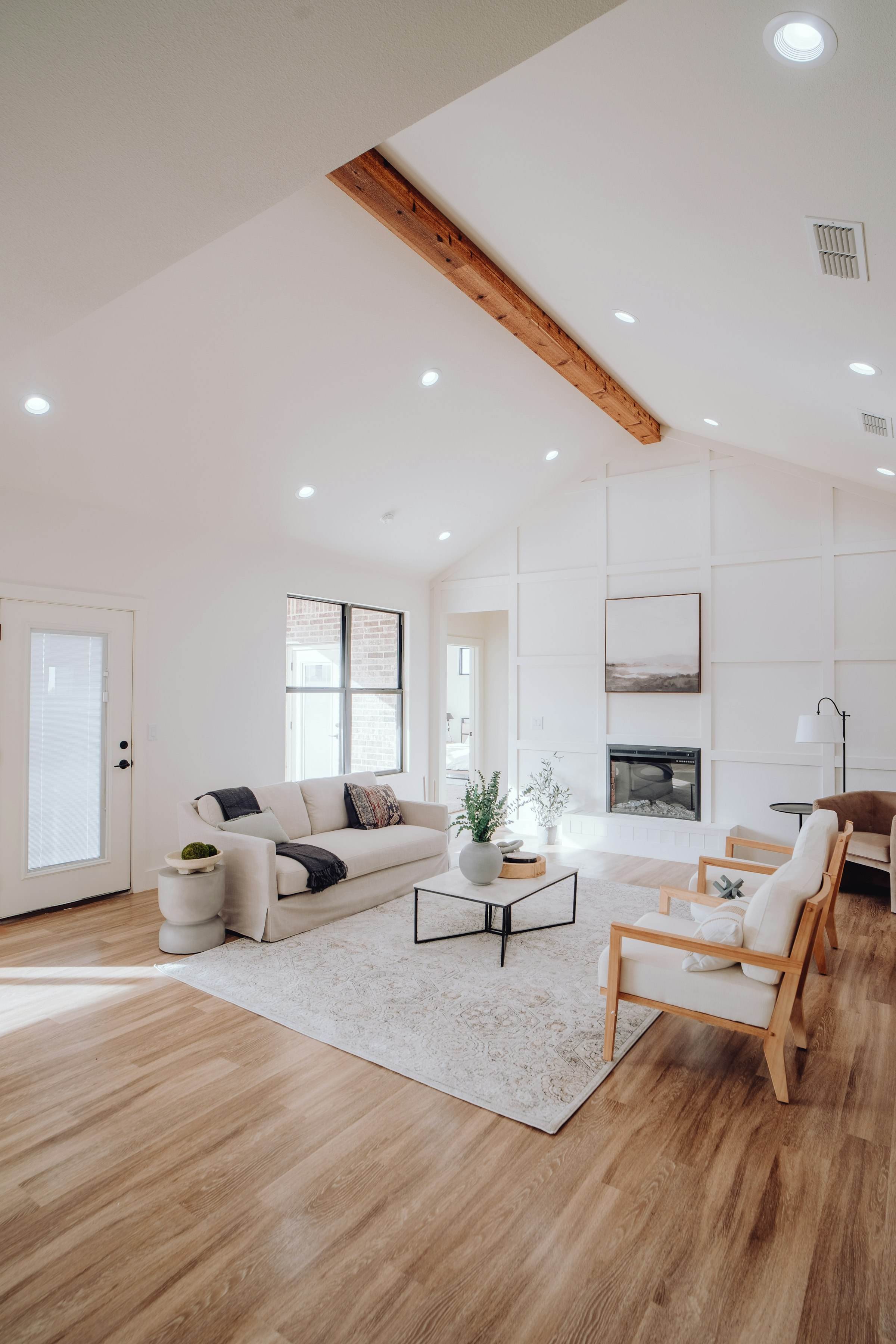 A living room with a vaulted ceiling, exposed beam and fireplace