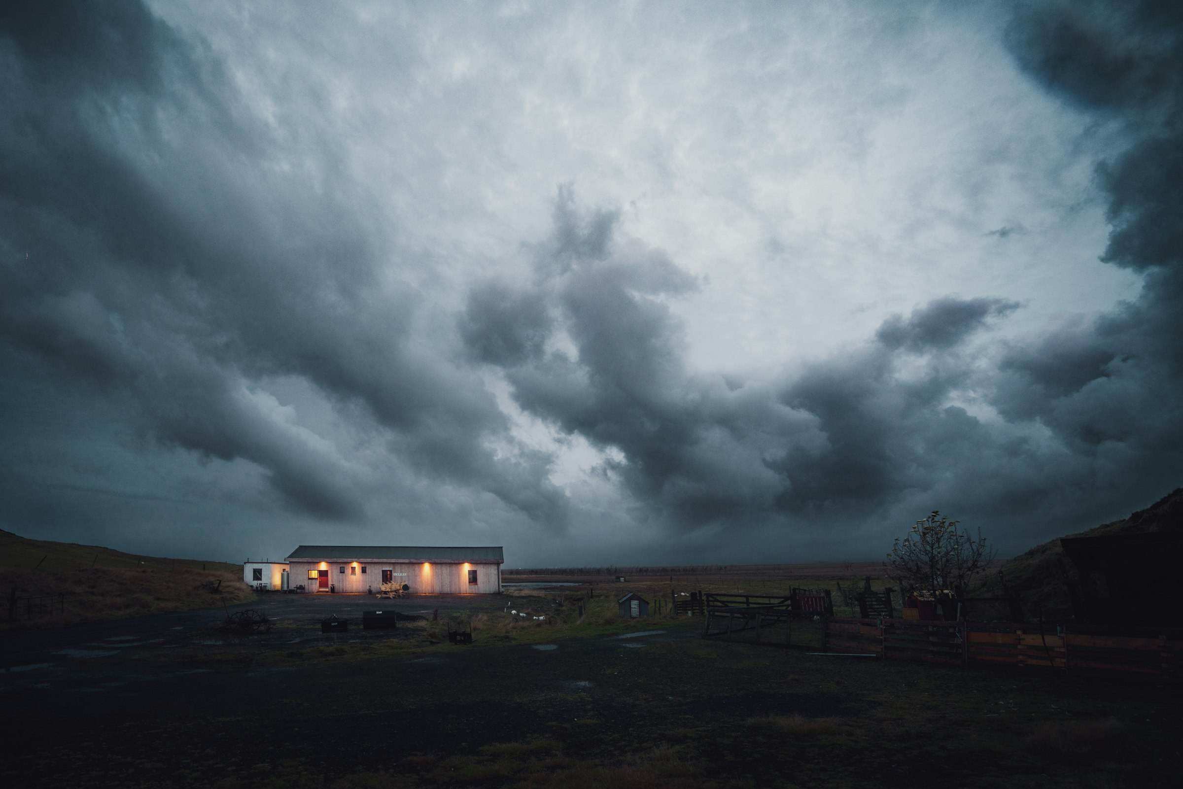 Heavy storm clouds over a lit house at dusk